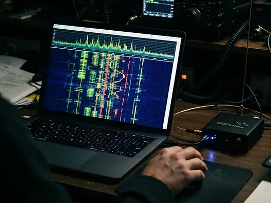 Laptop screen showing a digital mode waterfall display with signal traces